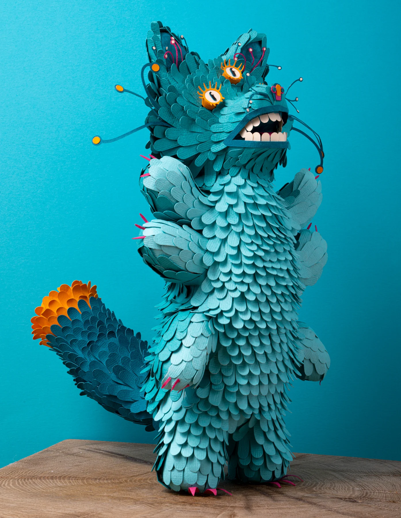 Renardus: a turquoise paper creature with orange eyes against a turquoise background