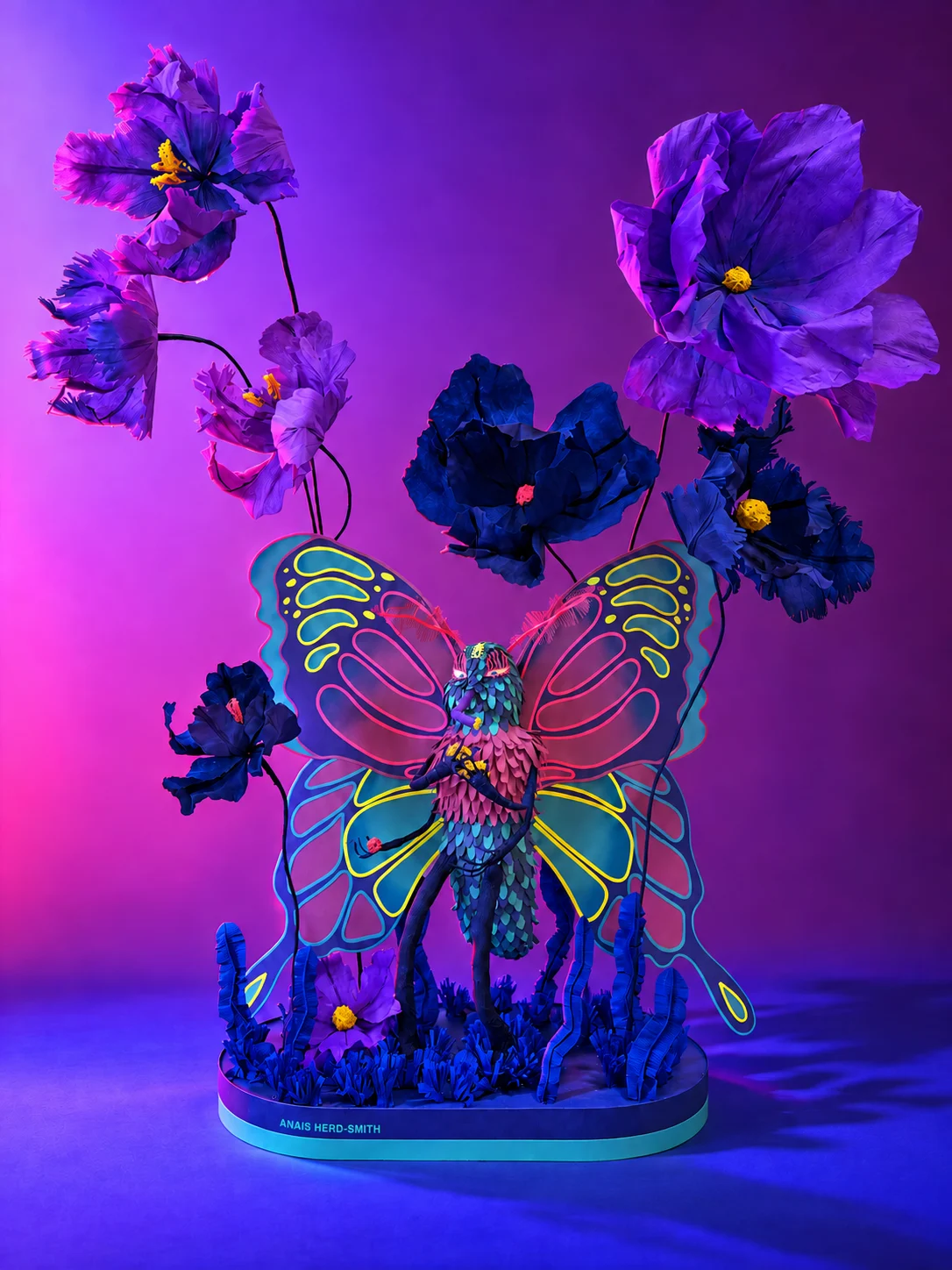 A colourful paper butterfly sculpture surrounded by purple flowers